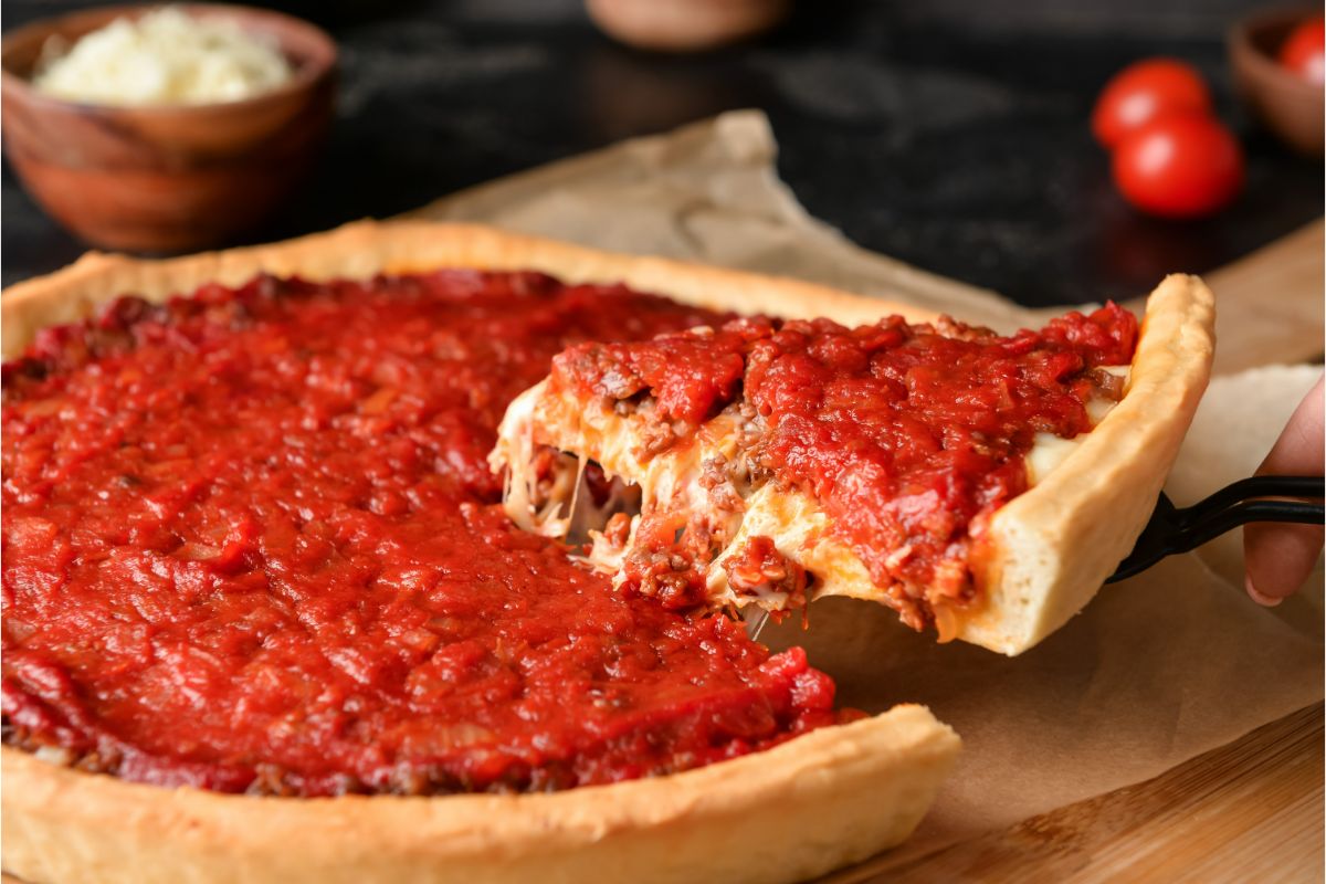 Detailed image shows a woman enjoying a delicious Chicago-style pizza on a dark background.