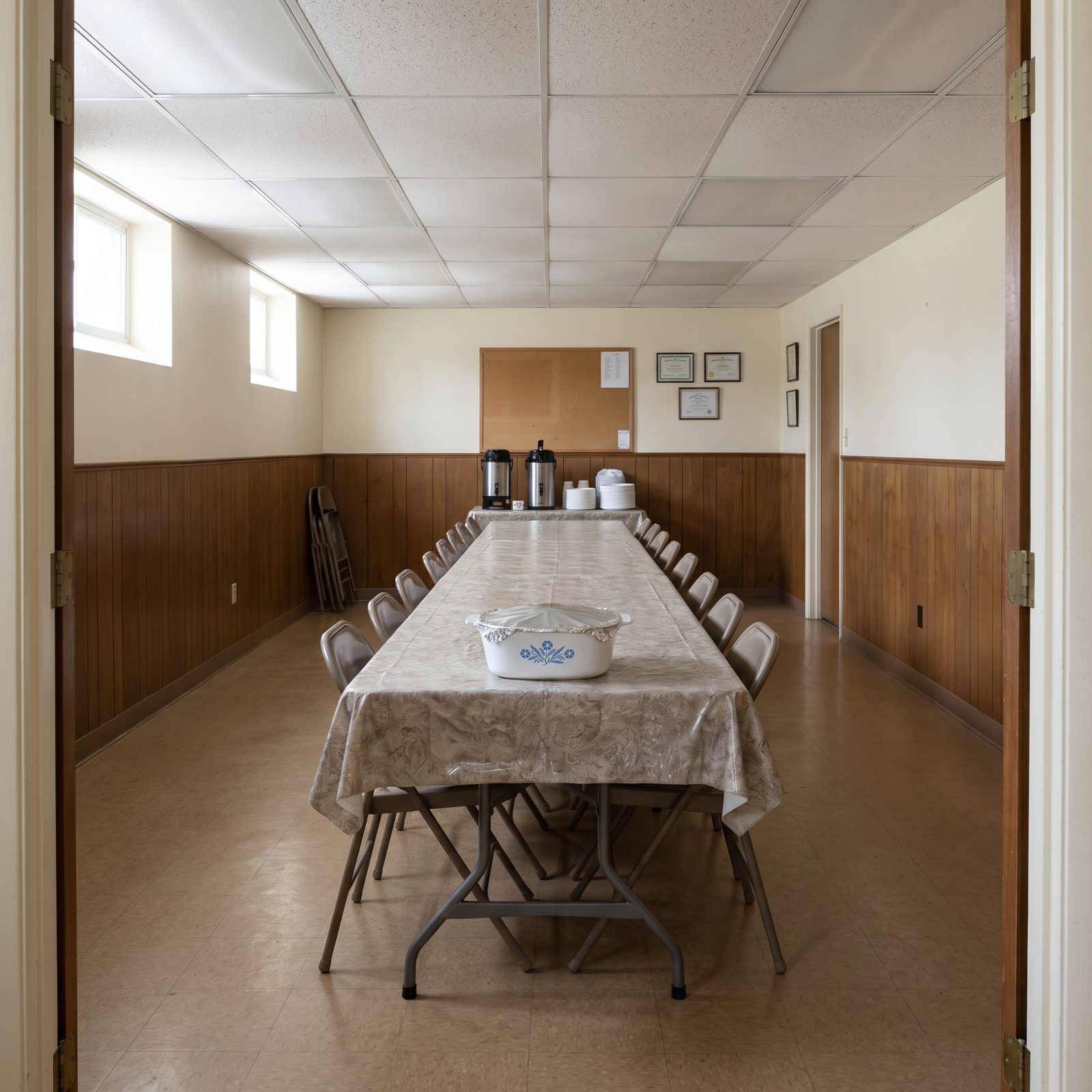 Church basement hall with one foil-covered casserole dish alone on a long folding table.